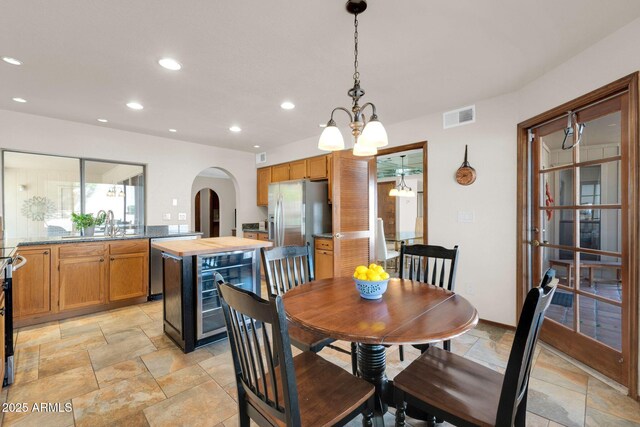 dining room featuring visible vents, beverage cooler, stone tile flooring, recessed lighting, and arched walkways