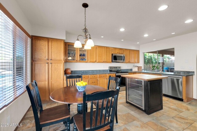 kitchen featuring recessed lighting, stainless steel appliances, hanging light fixtures, glass insert cabinets, and butcher block counters