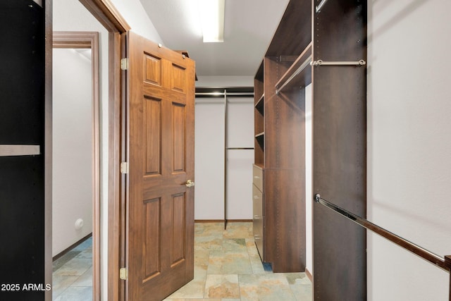 spacious closet featuring stone finish floor