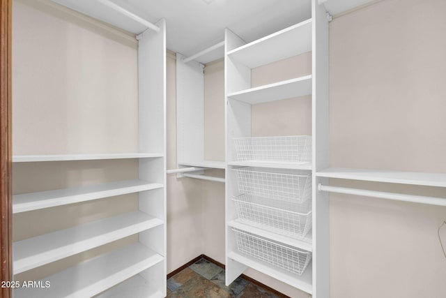 walk in closet with stone finish floor