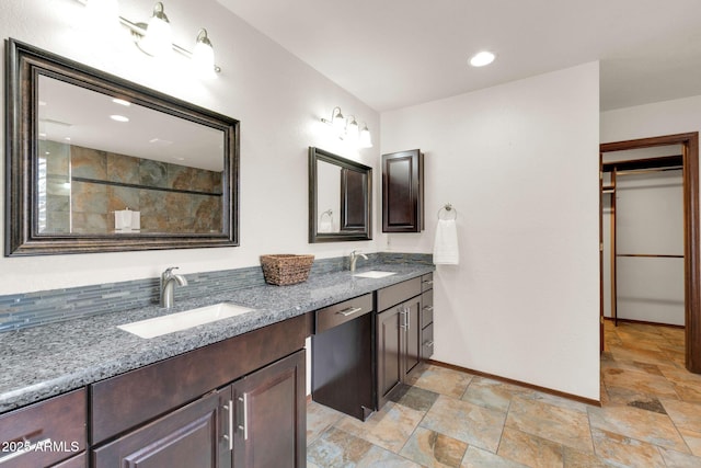 bathroom with double vanity, stone finish floor, baseboards, and a sink