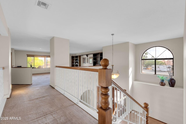 corridor featuring an upstairs landing, visible vents, and carpet floors