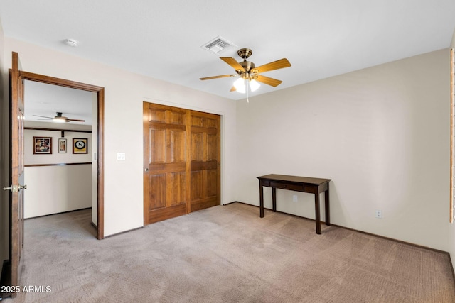 unfurnished bedroom featuring a closet, visible vents, light colored carpet, and a ceiling fan