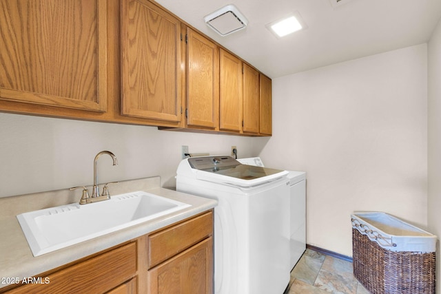 clothes washing area with a sink, stone finish flooring, cabinet space, and separate washer and dryer