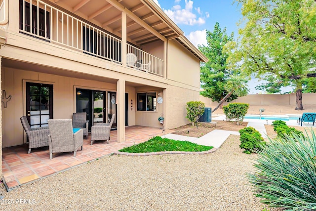 exterior space with central AC unit, a balcony, and a fenced in pool