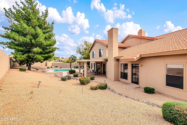 rear view of property featuring a patio area, stucco siding, a tiled roof, and a fenced backyard