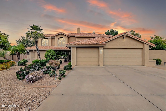 mediterranean / spanish home featuring fence, stucco siding, concrete driveway, a garage, and a tiled roof