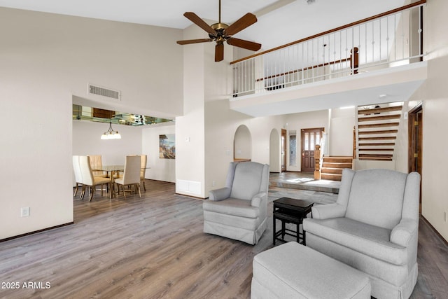 living room with visible vents, stairs, wood finished floors, arched walkways, and a ceiling fan