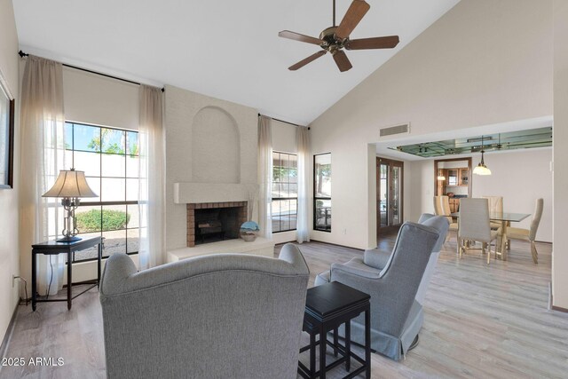 living area with a wealth of natural light, visible vents, light wood-style flooring, and a fireplace