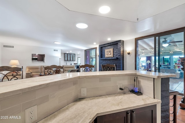kitchen with a kitchen breakfast bar, a large fireplace, and light stone counters