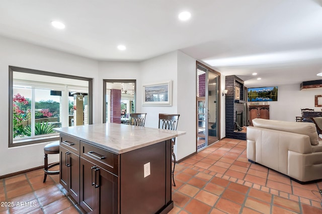 kitchen featuring a kitchen island, a kitchen bar, dark brown cabinetry, and light tile patterned floors