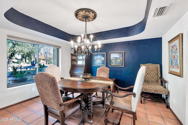 dining room with tile patterned flooring, a tray ceiling, and an inviting chandelier