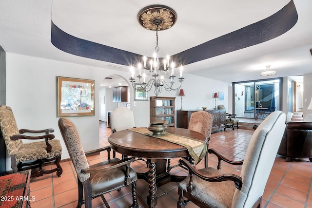 tiled dining space with a notable chandelier and a tray ceiling