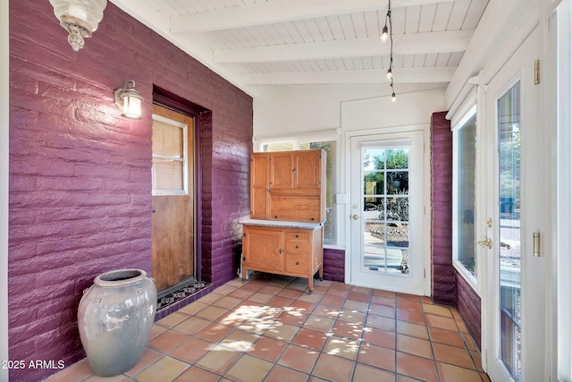 interior space with vaulted ceiling with beams, light tile patterned flooring, wooden ceiling, and brick wall