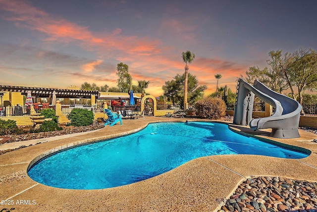 pool at dusk featuring a water slide