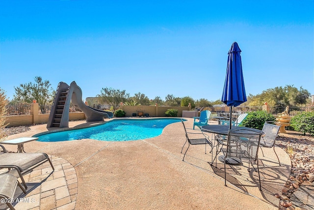 view of swimming pool with a water slide and a patio