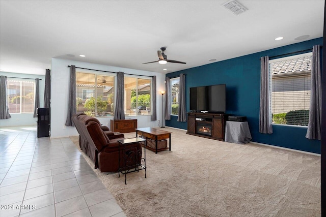 tiled living room with ceiling fan and a fireplace