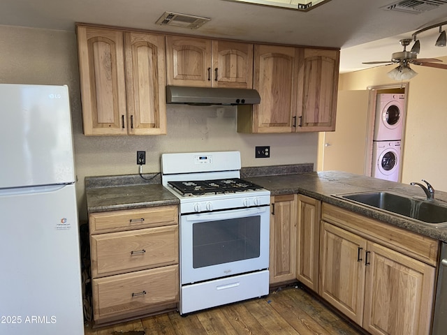 kitchen featuring white appliances, stacked washer and clothes dryer, ceiling fan, dark hardwood / wood-style flooring, and sink