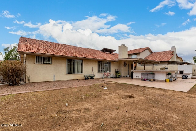 back of property with a patio area, a tiled roof, an outdoor kitchen, and stucco siding