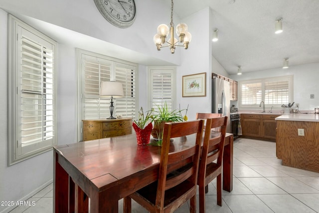 dining area with light tile patterned floors, lofted ceiling, and an inviting chandelier