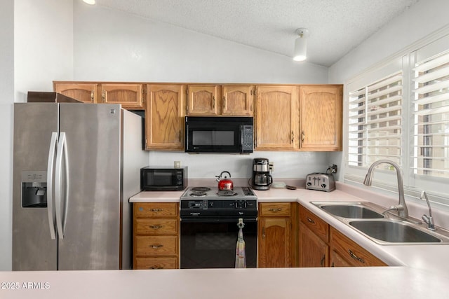 kitchen featuring vaulted ceiling, a textured ceiling, light countertops, black appliances, and a sink