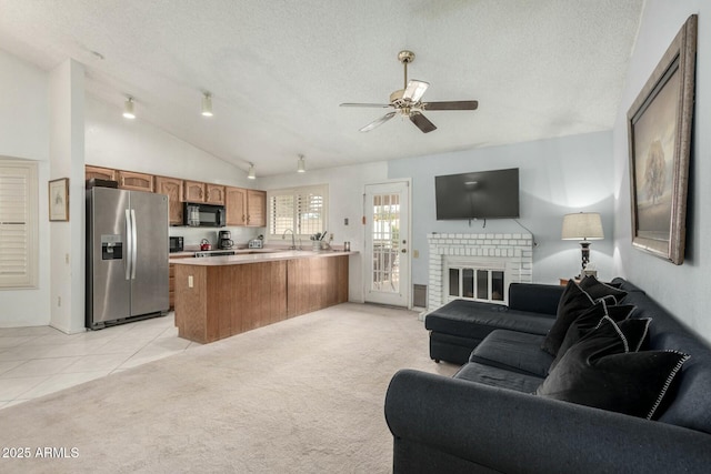 living area featuring lofted ceiling, a brick fireplace, light colored carpet, and a textured ceiling