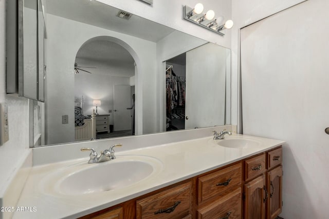 bathroom with double vanity, a spacious closet, visible vents, and a sink