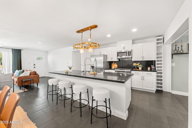 kitchen with tasteful backsplash, white cabinets, a breakfast bar area, hanging light fixtures, and stainless steel appliances