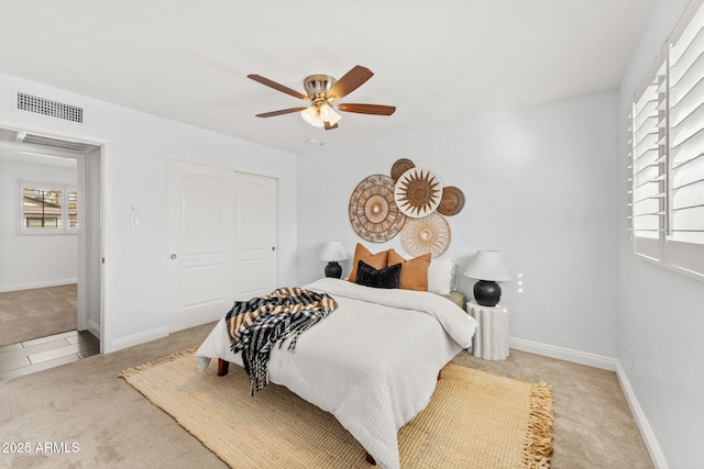 carpeted bedroom with a ceiling fan, a closet, visible vents, and baseboards