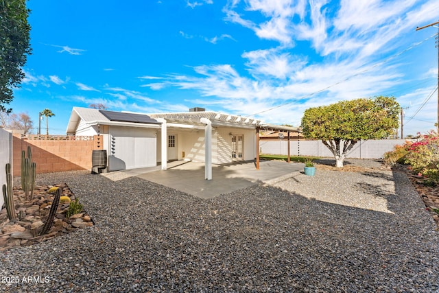 back of house with a patio area, a fenced backyard, roof mounted solar panels, and a pergola