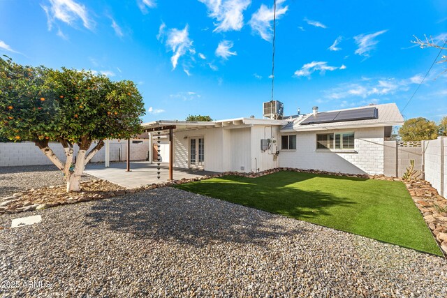 back of property featuring french doors, solar panels, a patio, a fenced backyard, and a yard