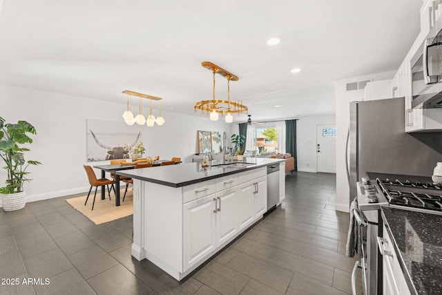 kitchen with stainless steel appliances, hanging light fixtures, white cabinetry, a sink, and a kitchen island