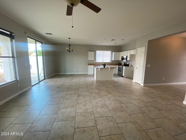 unfurnished living room featuring ceiling fan with notable chandelier and light tile patterned flooring