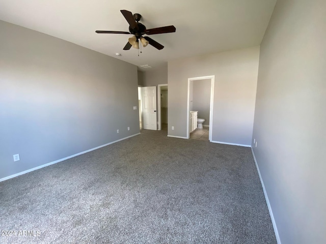 unfurnished bedroom featuring connected bathroom, a spacious closet, ceiling fan, and dark colored carpet