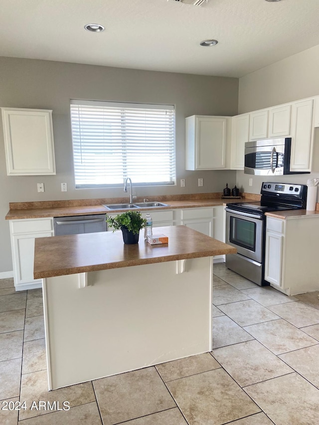 kitchen featuring stainless steel appliances, white cabinetry, a center island, and sink