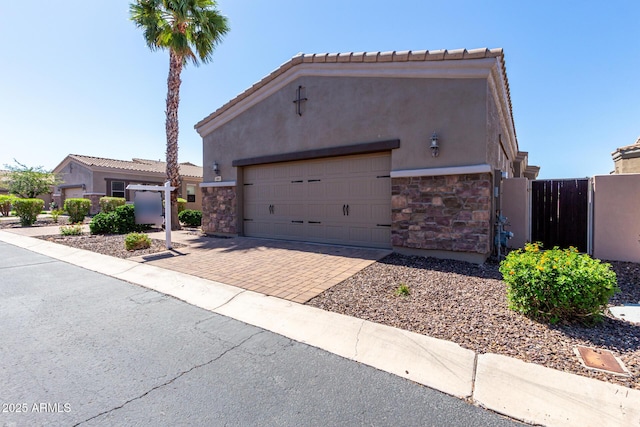 6202 E Mckellips Rd Unit 183, Mesa, AZ 85215 - view of front of property with stone siding, stucco siding, decorative driveway, a gate, and an attached garage