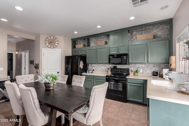 kitchen with tasteful backsplash, black appliances, sink, light tile patterned floors, and green cabinetry