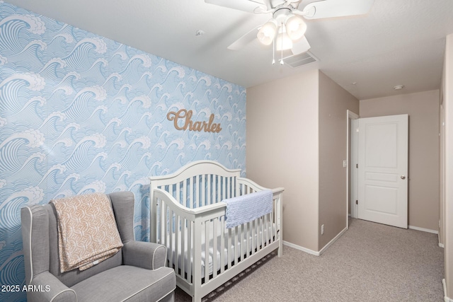 carpeted bedroom featuring ceiling fan and a crib