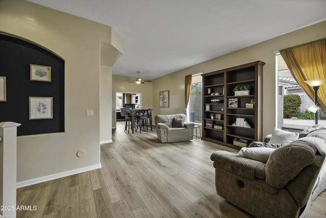 living room with ceiling fan, plenty of natural light, light wood-style flooring, and baseboards