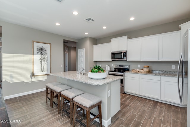 kitchen featuring white cabinets, appliances with stainless steel finishes, and a center island with sink