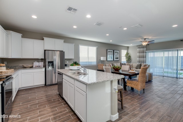 kitchen with white cabinets, a kitchen island with sink, and appliances with stainless steel finishes