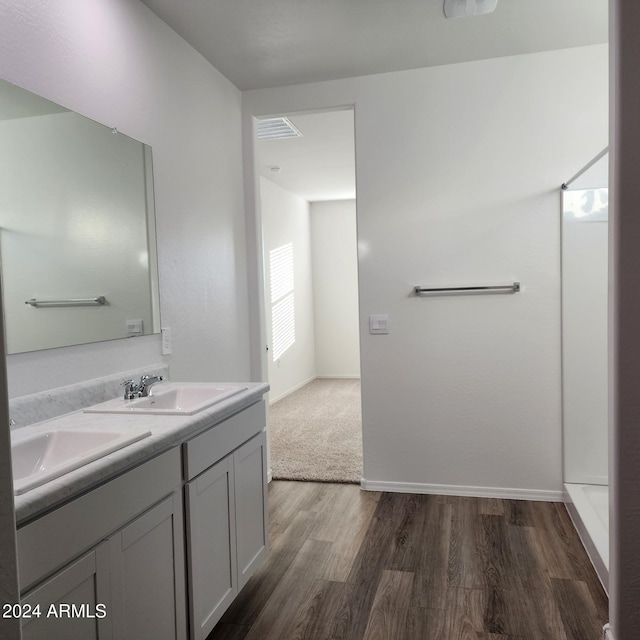 bathroom with walk in shower, vanity, and hardwood / wood-style flooring