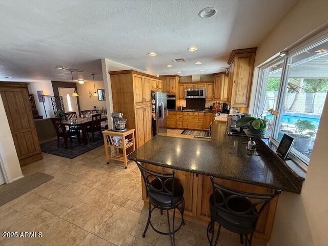 12601 N 34th St, Phoenix, AZ 85032 - kitchen with a peninsula, visible vents, a breakfast bar, dark countertops, and stainless steel appliances