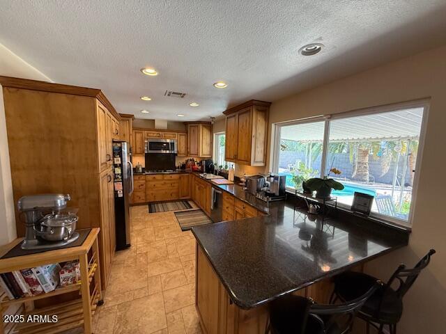12601 N 34th St, Phoenix, AZ 85032 - kitchen with a breakfast bar, recessed lighting, a peninsula, brown cabinets, and stainless steel appliances