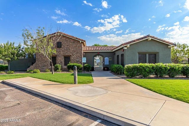 19576 N Portarosa Ct, Maricopa, AZ 85138 - mediterranean / spanish home with stucco siding, a tiled roof, a front yard, and stone siding