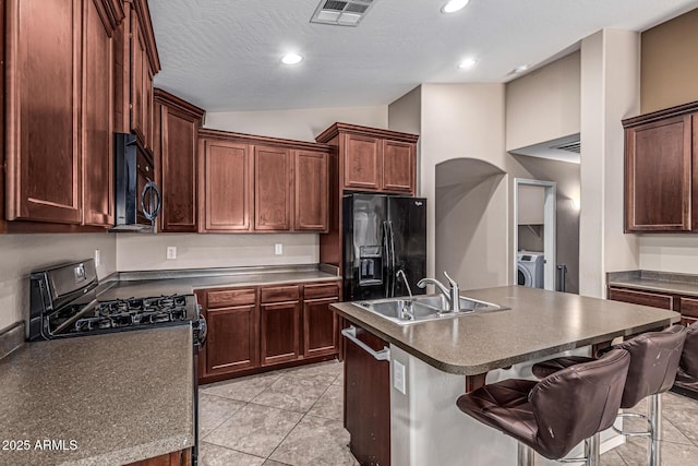 19576 N Portarosa Ct, Maricopa, AZ 85138 - kitchen with black appliances, a sink, lofted ceiling, dark countertops, and washing machine and dryer