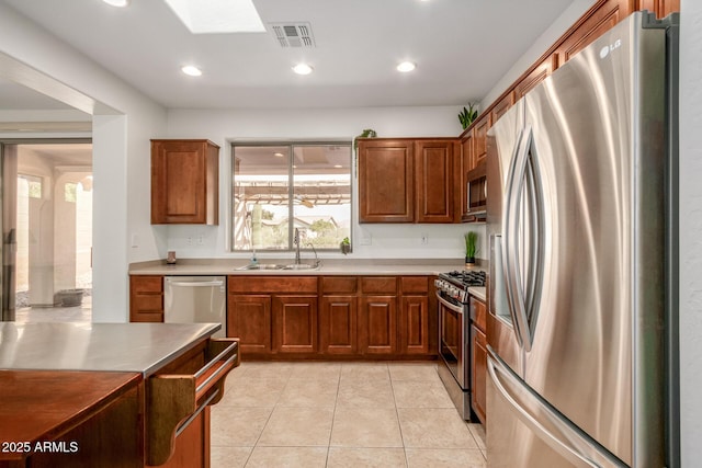 kitchen featuring visible vents, appliances with stainless steel finishes, brown cabinetry, a sink, and plenty of natural light