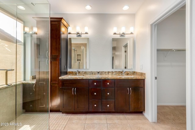 full bath featuring double vanity, tile patterned flooring, a sink, and a shower stall