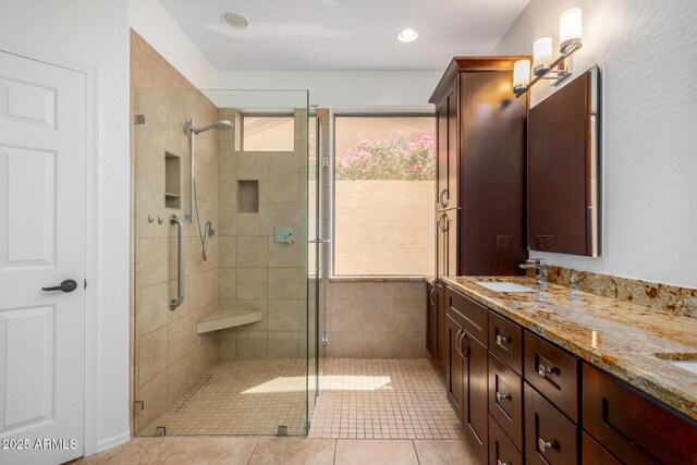 bathroom featuring double vanity, a stall shower, tile patterned flooring, and a sink