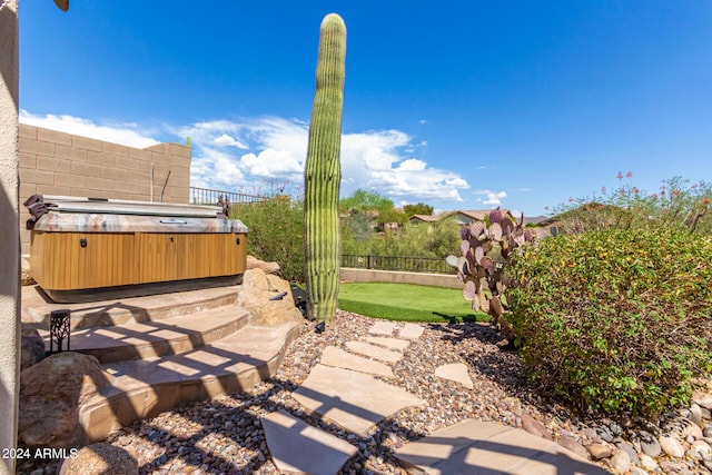 view of patio with a hot tub and fence